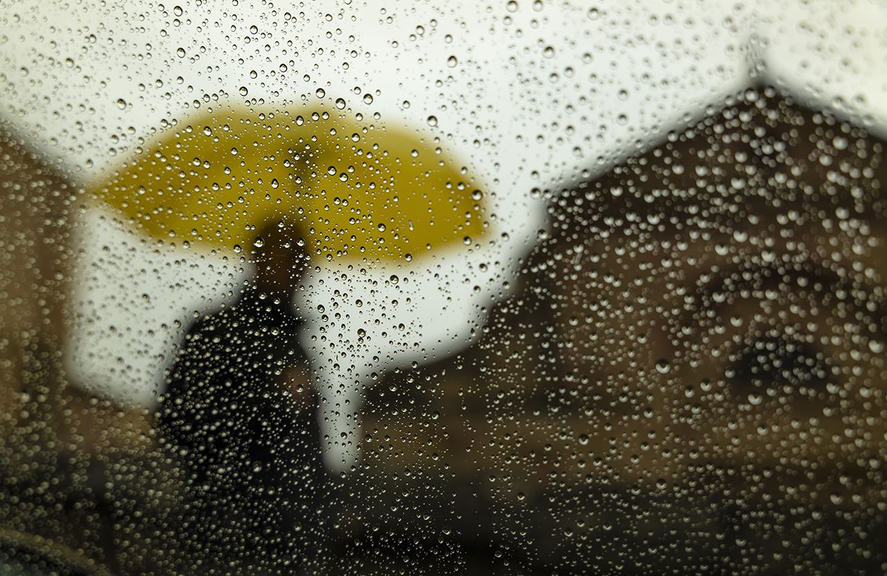 Person-with-umbrella-behind-blurry-windowpane